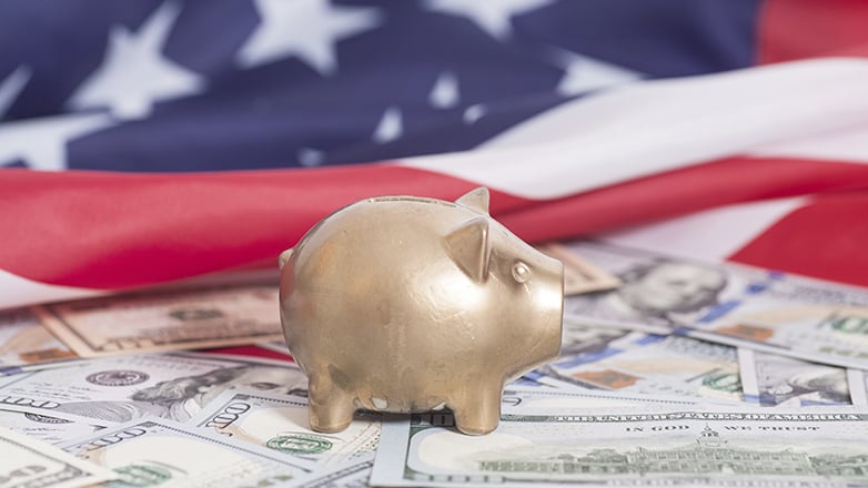 piggy bank on money in front of american flag